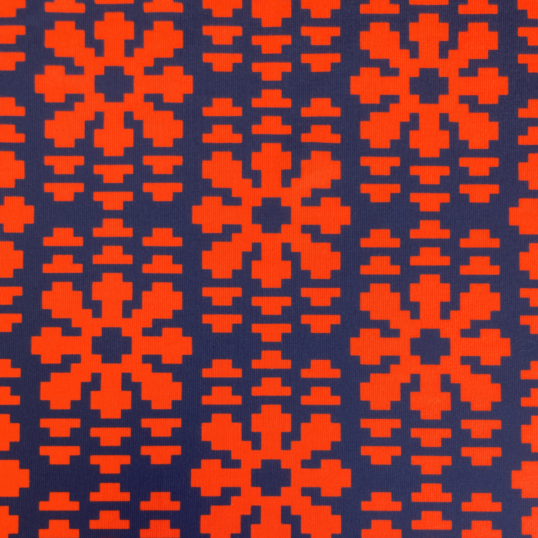 Broadcast Blooms echoing pixelated starburst repeat pattern in scarlet red on a dark navy blue background.